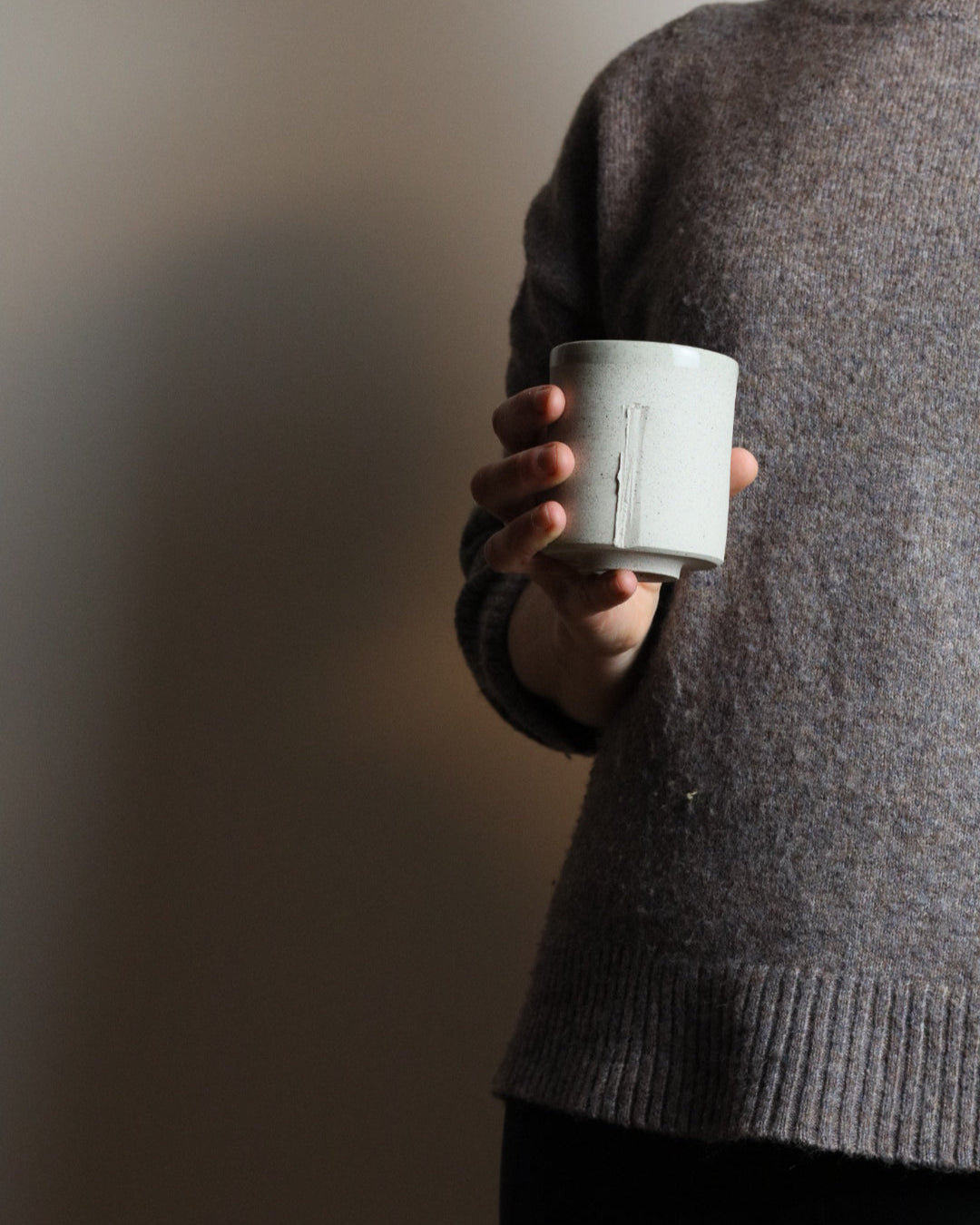 Person holding a ceramic tumbler against a plain background