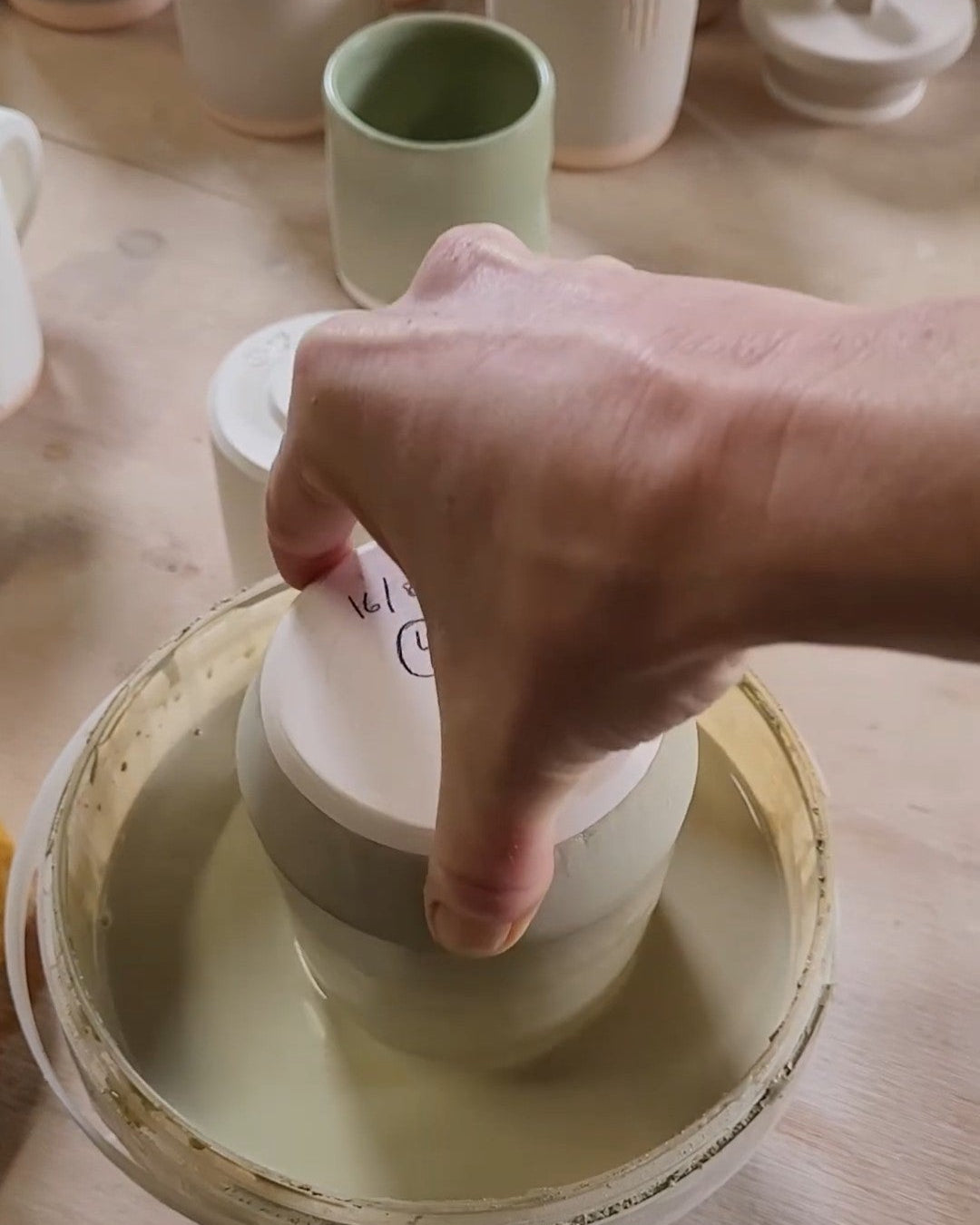 Person dip glazing a ceramic mug