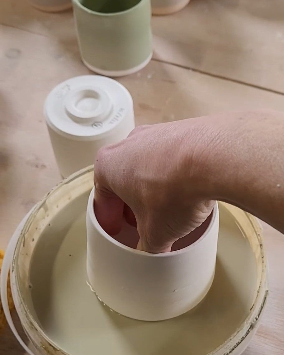 Person dip glazing a ceramic mug