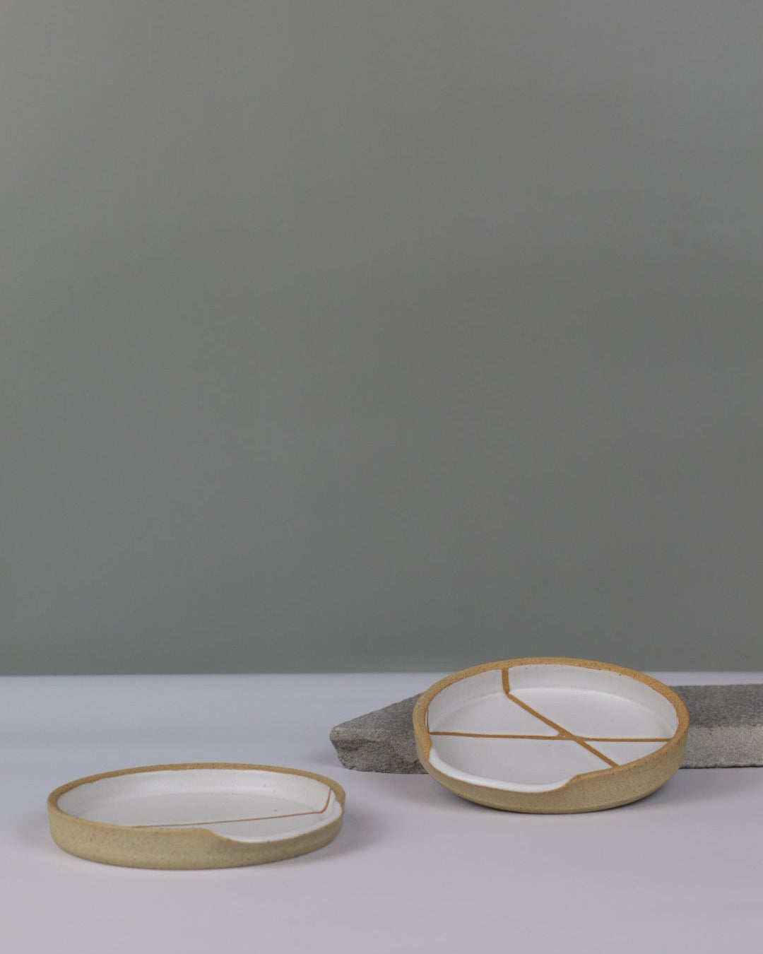 two white ceramic spoon rests on a benchtop