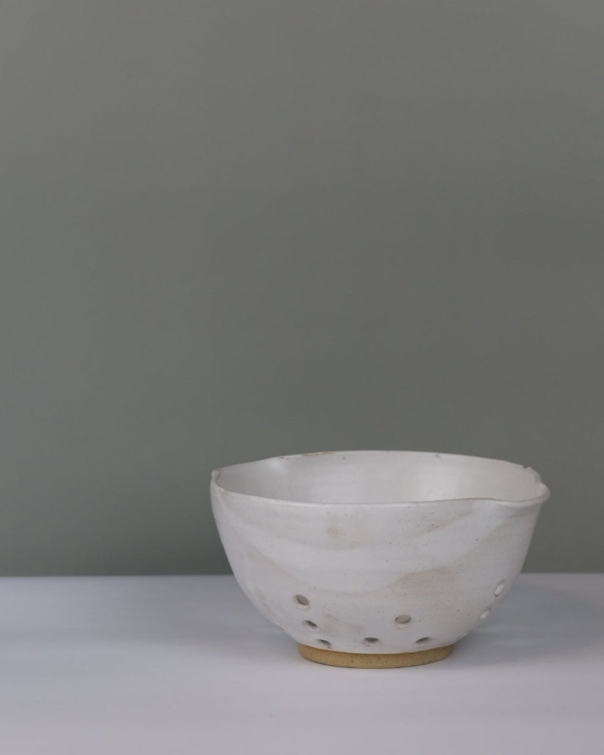white colander on a grey background