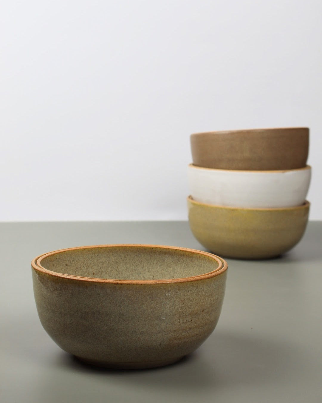 Set of ceramic bowls in various colors on a neutral background
