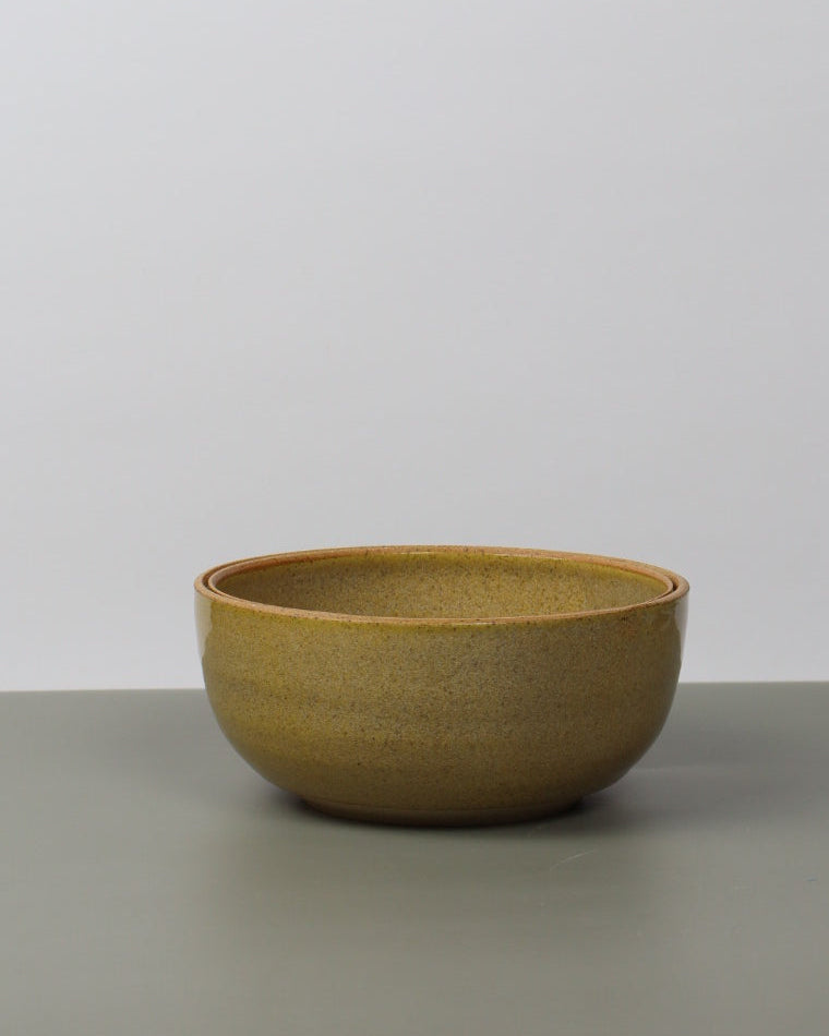 Yellow ceramic bowl leaning against a white wall
