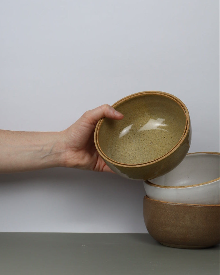 Hand holding a ceramic bowl against a plain background