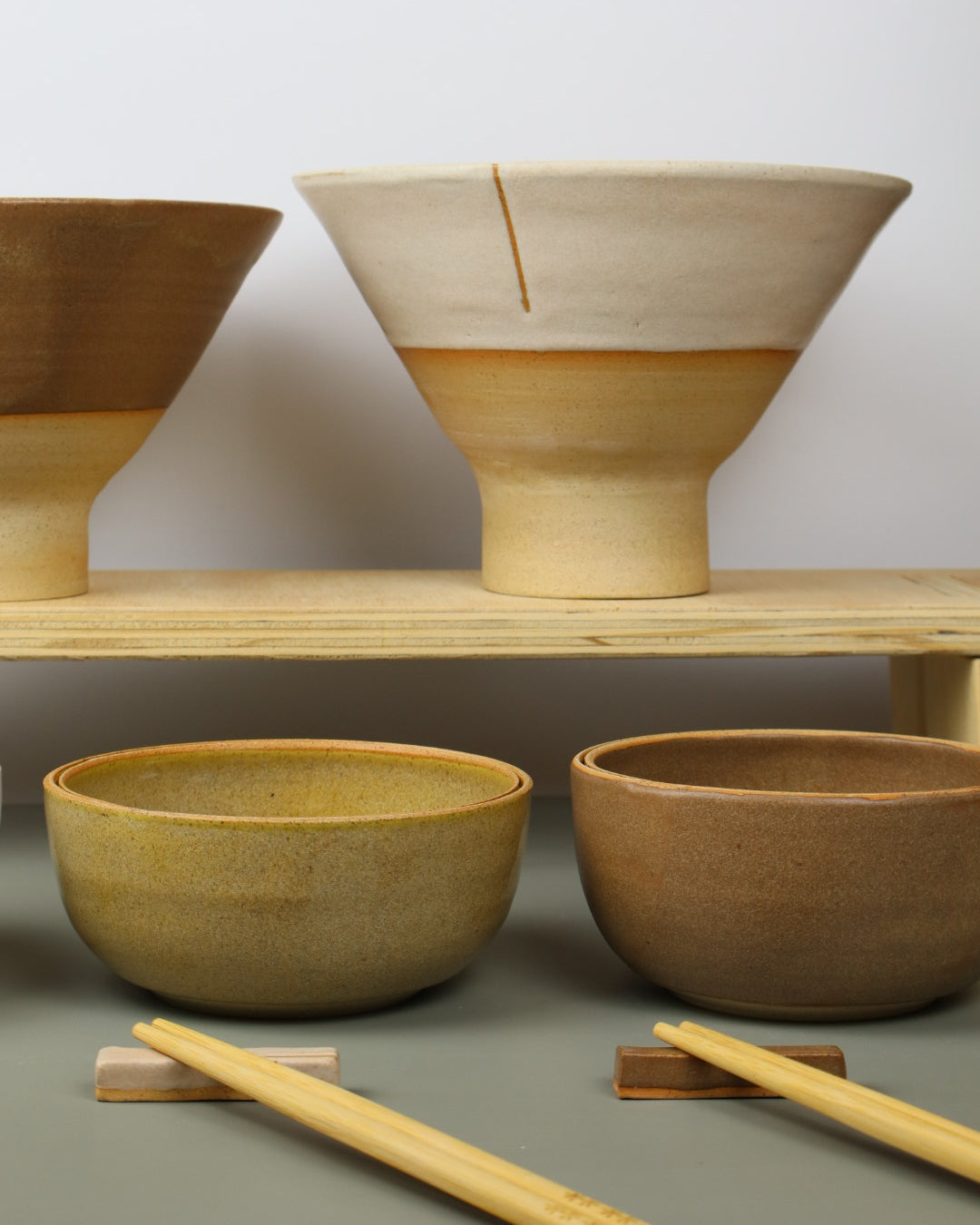 Ceramic bowls on a shelf against a wall with a neutral background