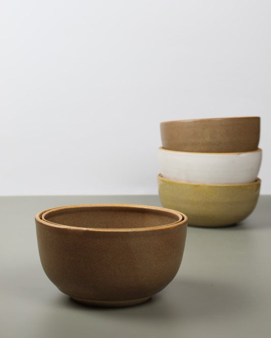 Two ceramic bowls of different sizes against a white wall.