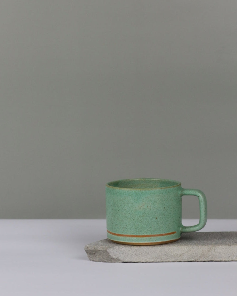 Green ceramic cup with line against a gray background