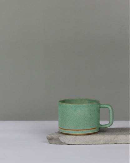 Green ceramic cup with line against a gray background