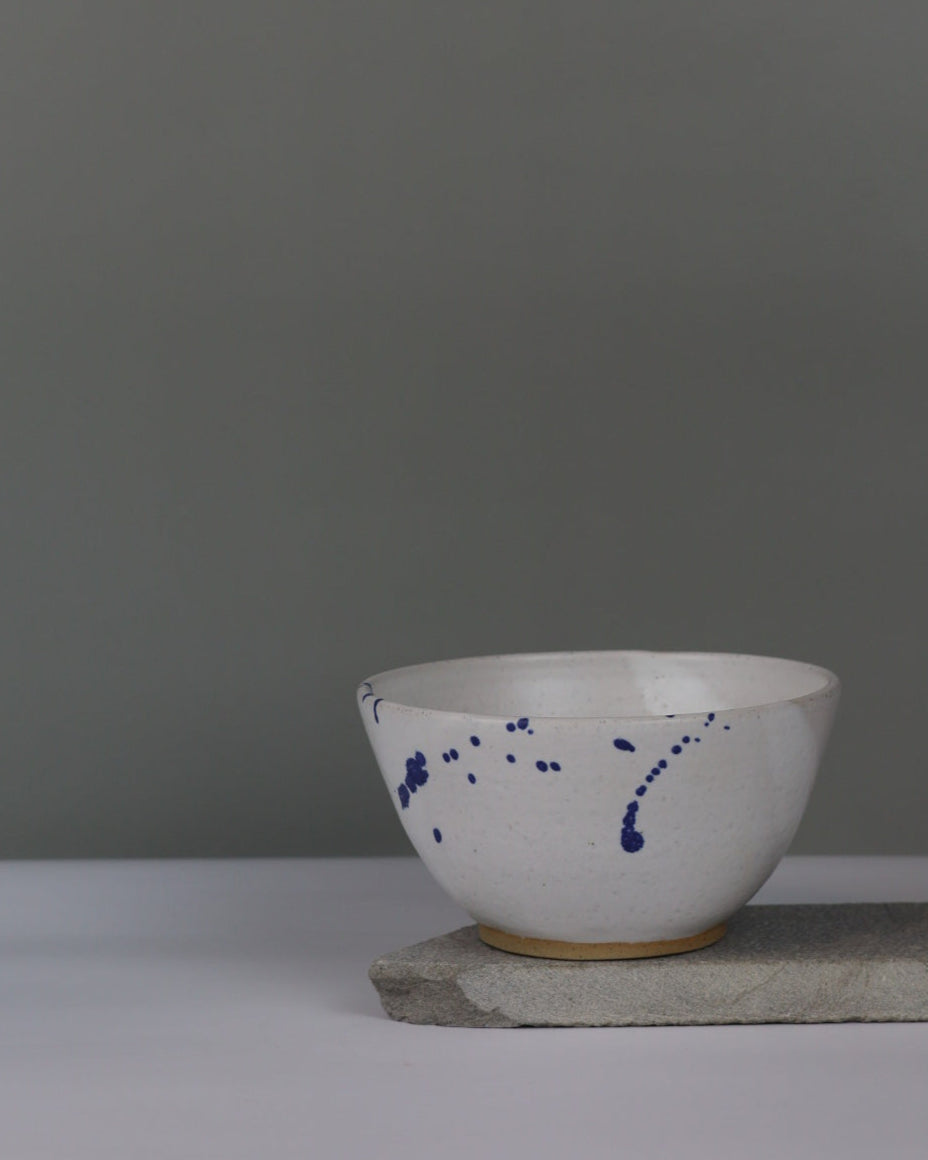 White and blue splatter ceramic bowl on a grey background