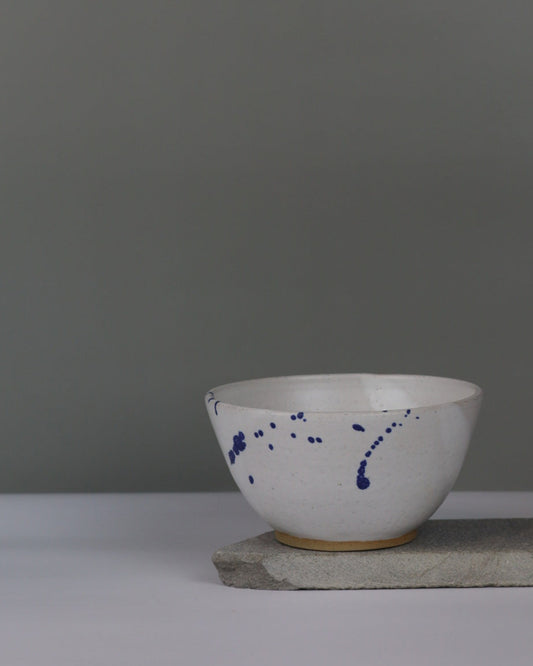 White and blue splatter ceramic bowl on a grey background