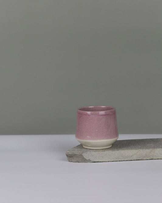 Small pink ceramic tumbler against a grey background