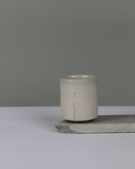Grey speckled ceramic tumbler against a grey background