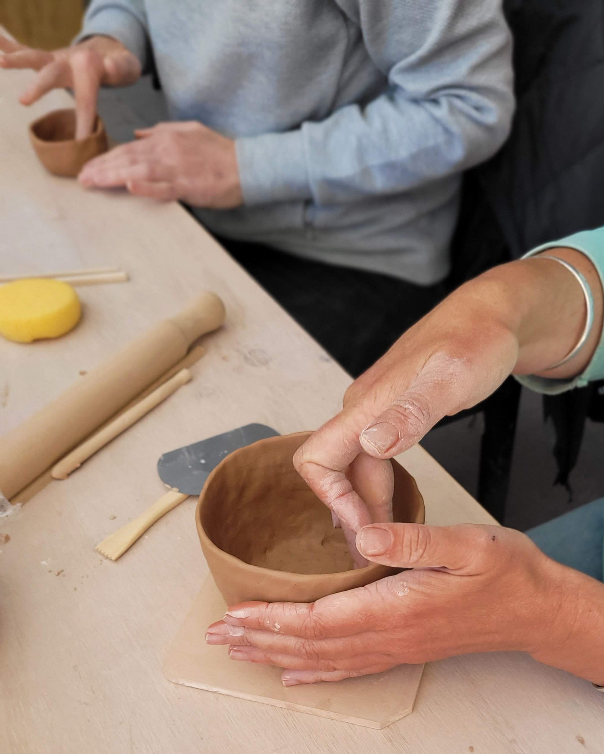 Person shaping a clay pot 