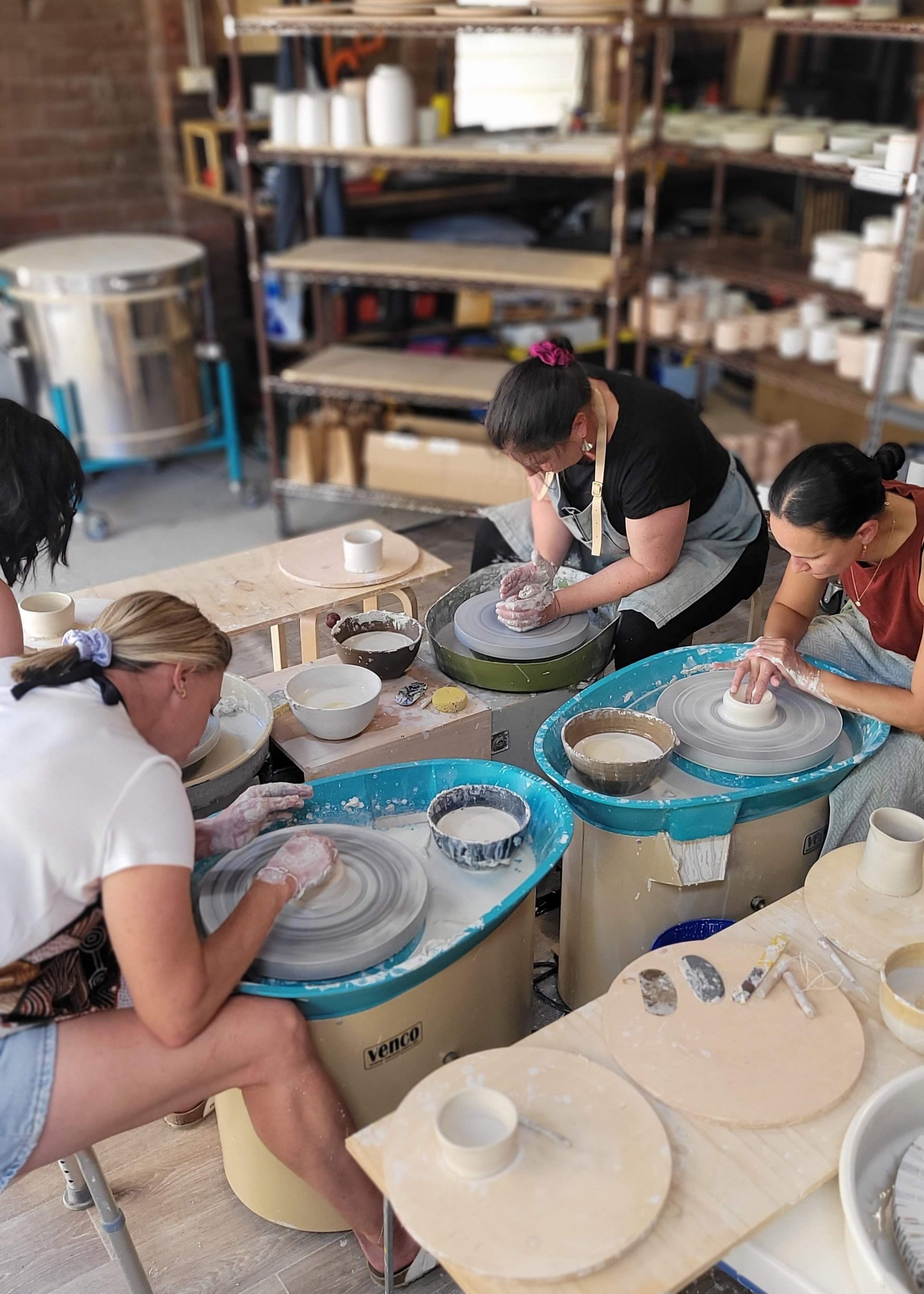 People using pottery wheels in a studio setting