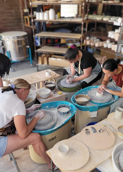 People using pottery wheels in a studio setting