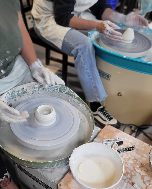 People working with pottery wheels in a studio setting