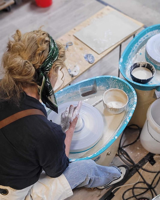 Person working with pottery on a wheel in a workshop setting