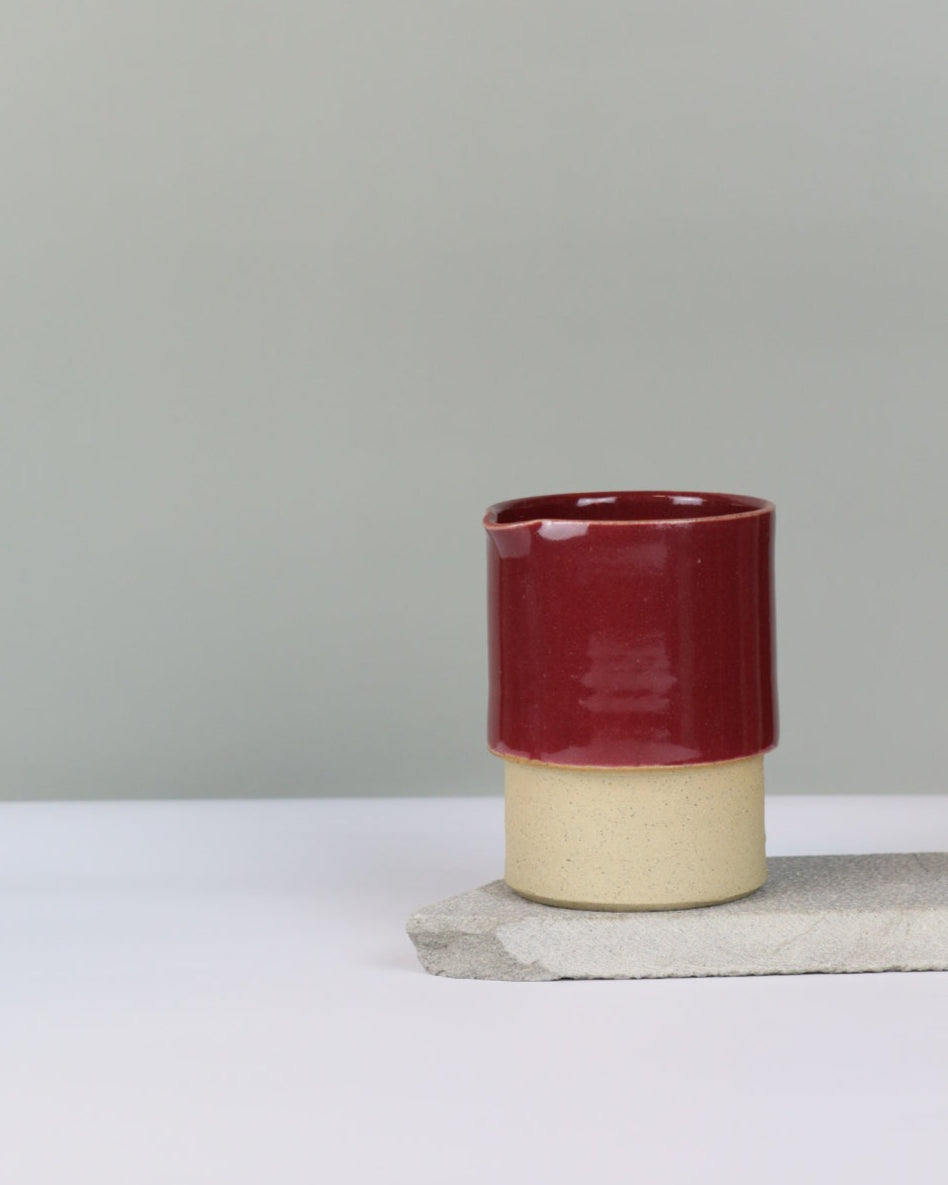 Ceramic jug in deep red on a grey background