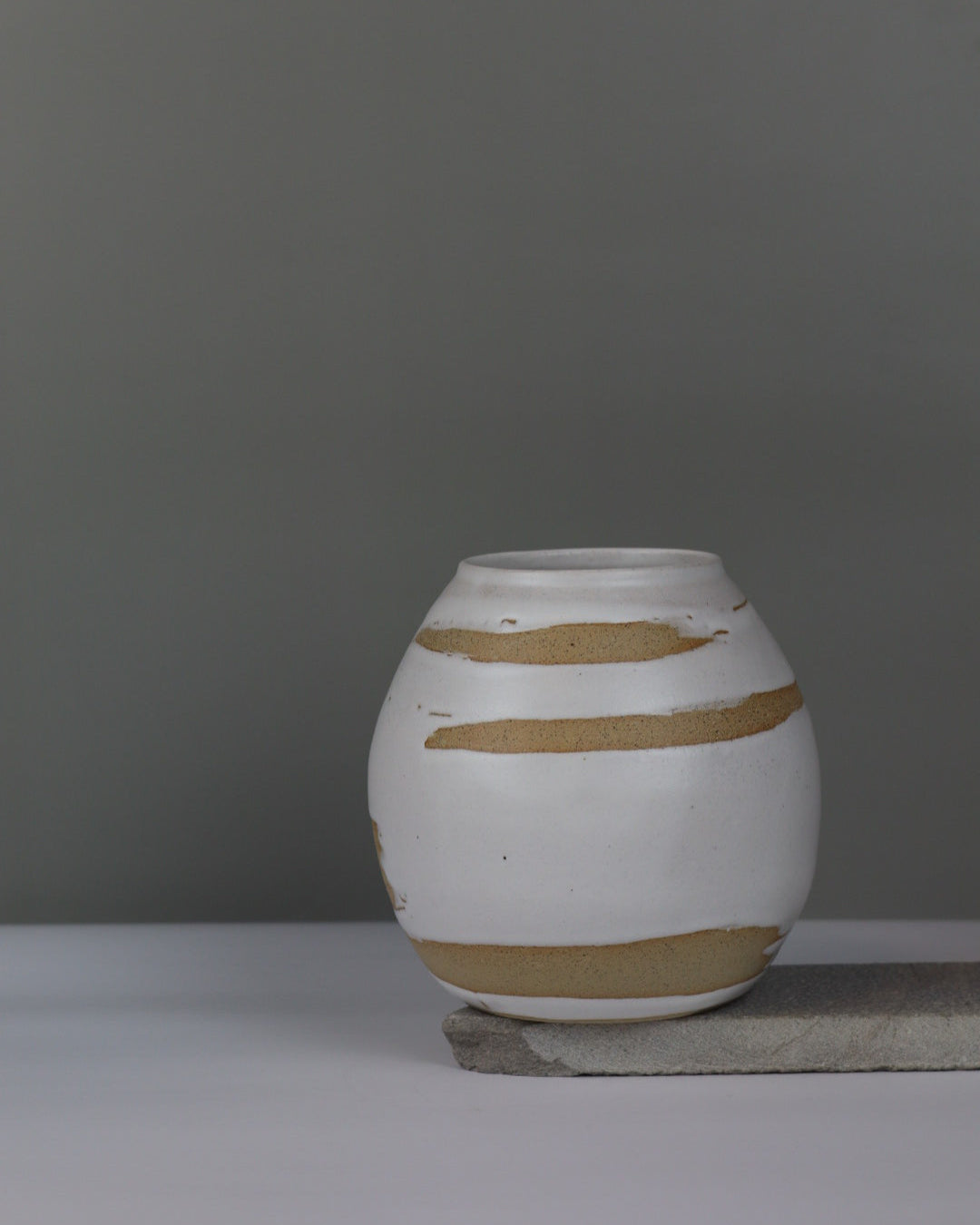 ceramic vase with white brushstrokes on a grey background