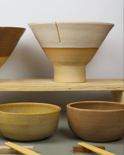 Ceramics bowls on a chelf with ceramic bowl in front of them 