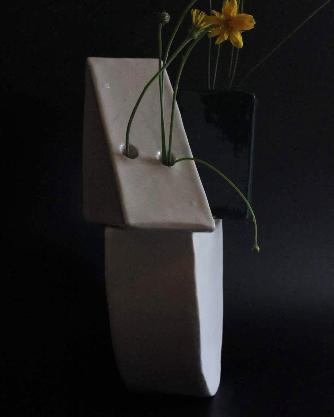 Abstract ceramic art piece with geometric shapes and flowers on a black background