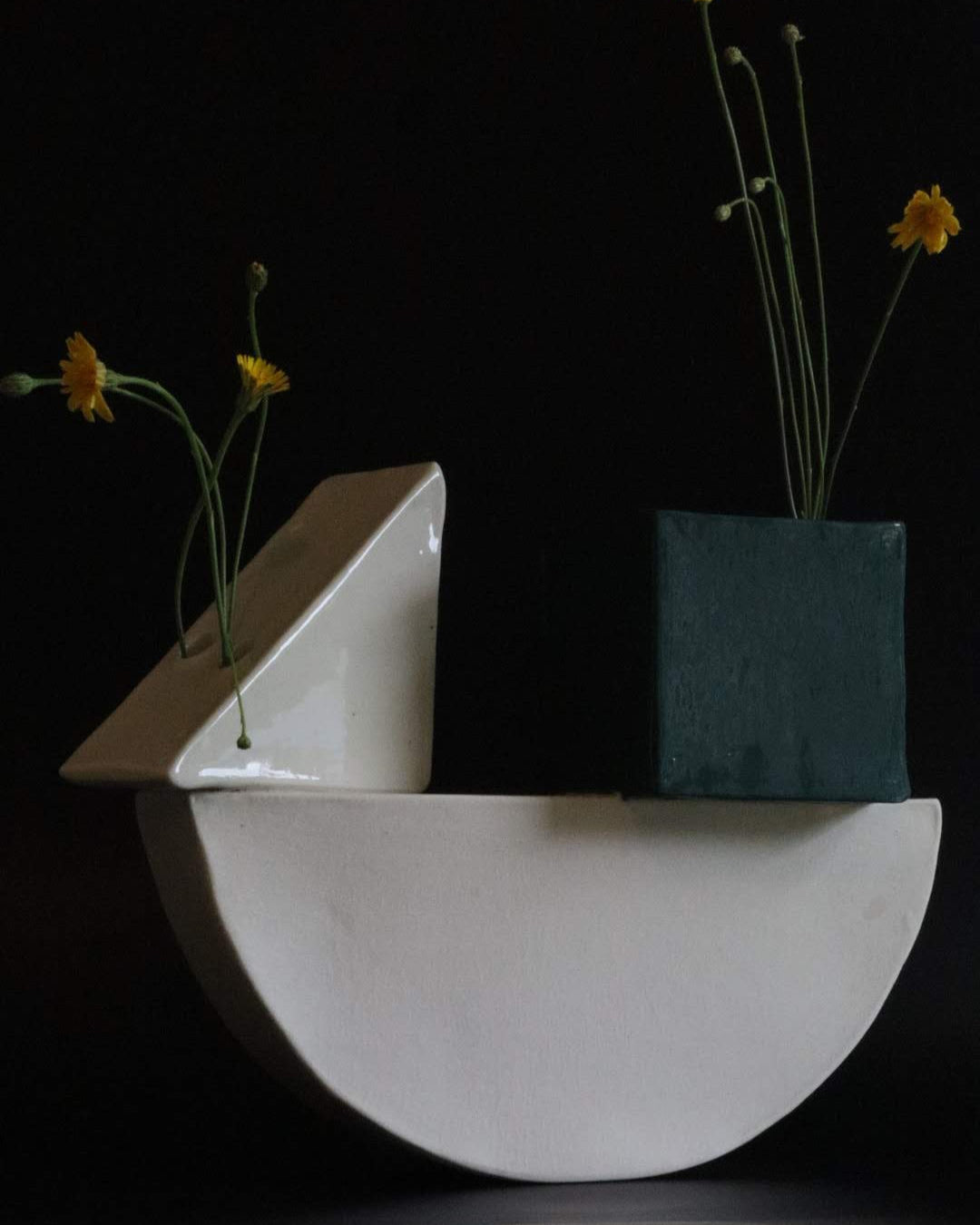 Abstract ceramic art piece with geometric shapes and flowers on a black background