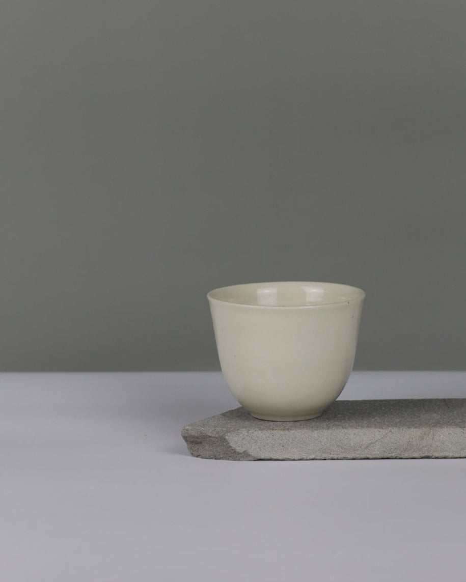 White ceramic teacup on a grey background