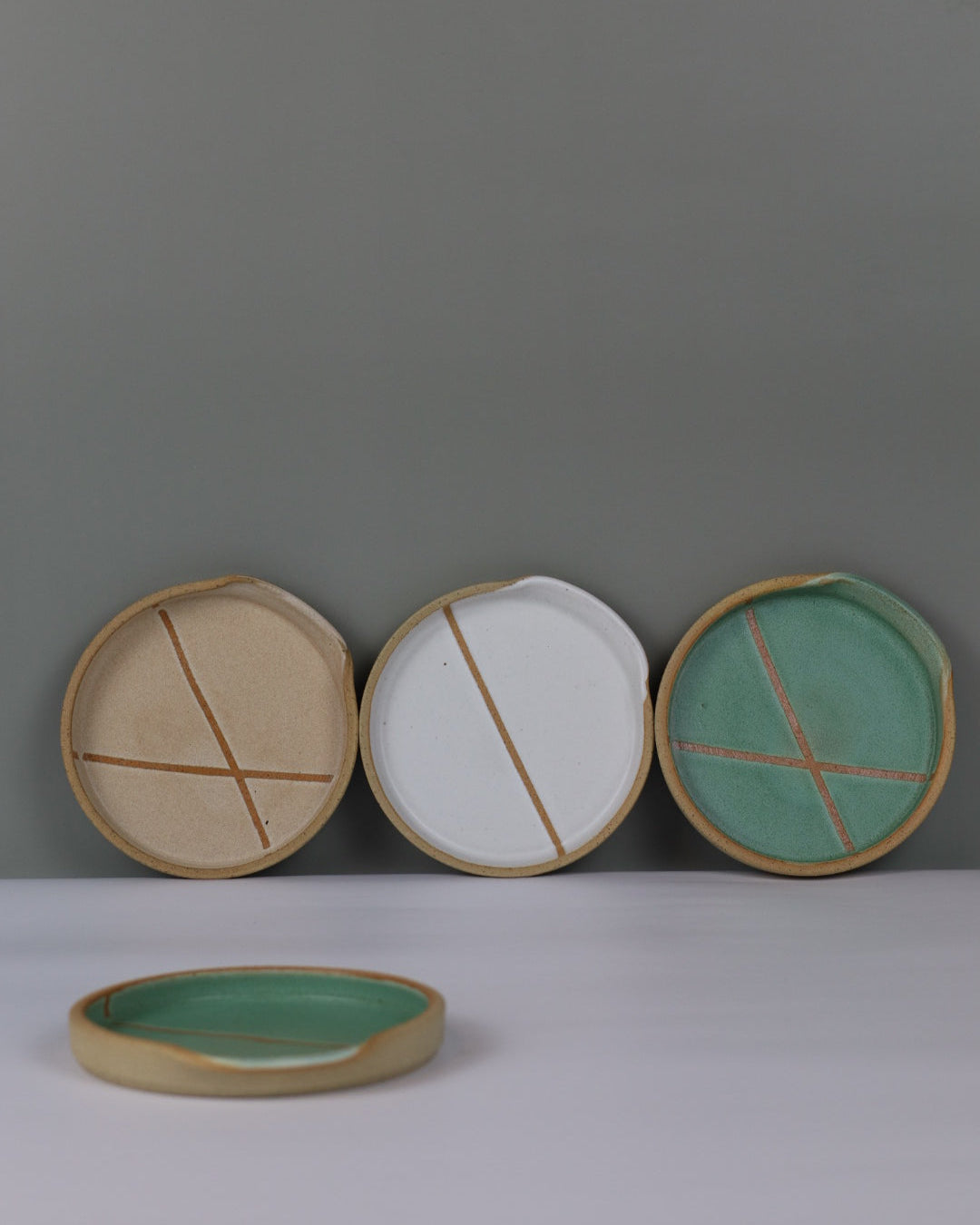 Set of ceramic spoon rests leaning against a wall.
