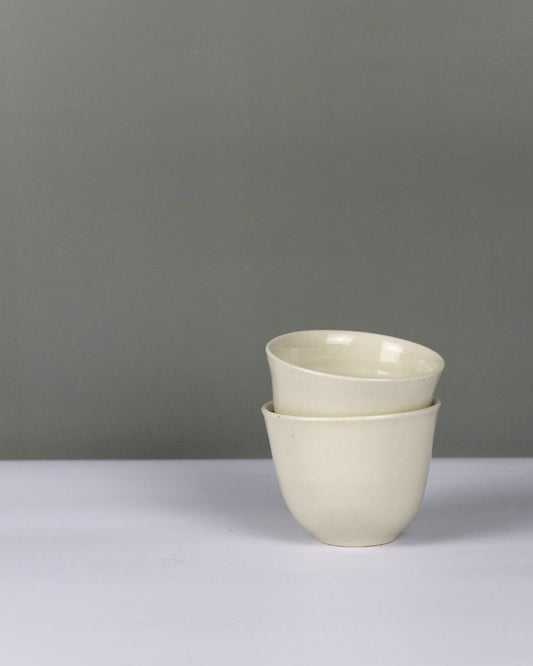 Stack of two white teacups on a grey background