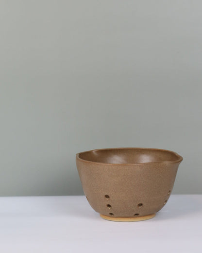 brown ceramic berry bowl on a grey background