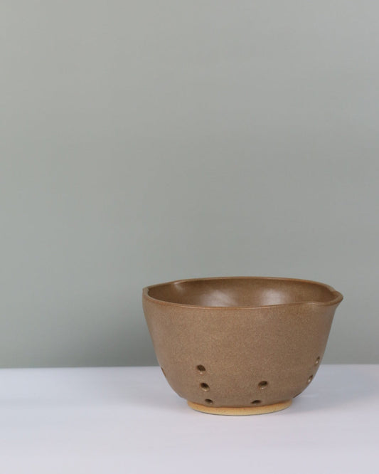 brown ceramic berry bowl on a grey background