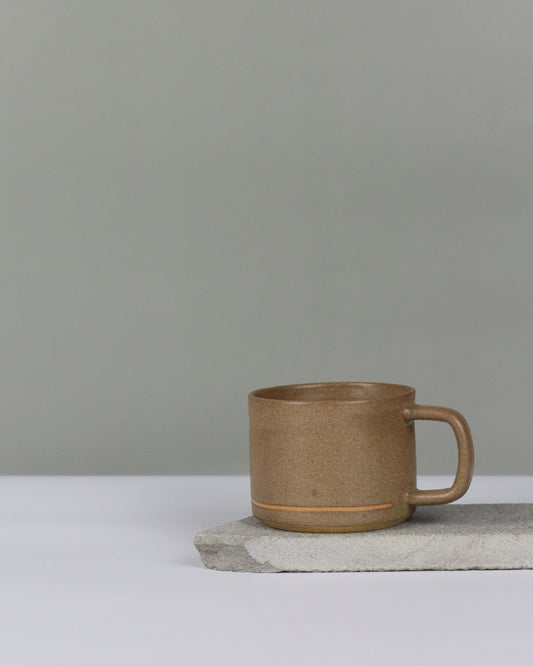 Brown ceramic cup with handle on a white surface