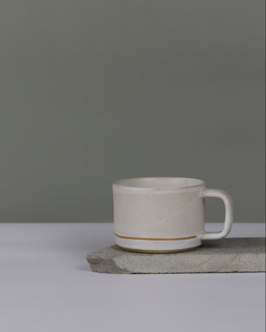 White ceramic cup with line on a grey background