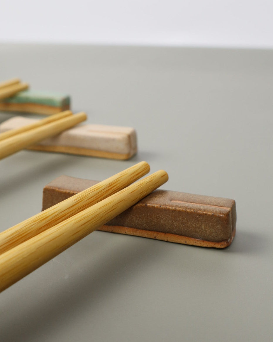 Wooden chopstick holder with wooden sticks on a light gray background