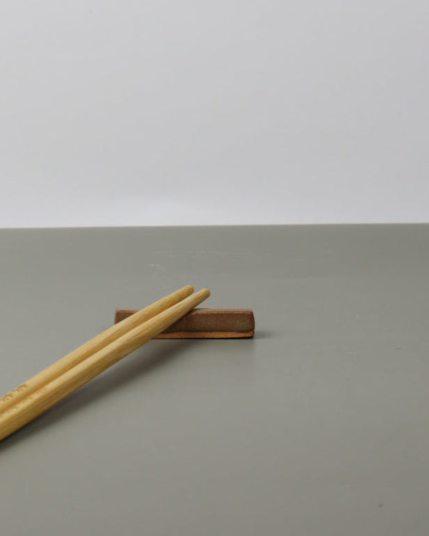 chopsticks resting on a ceramic chopstick rest