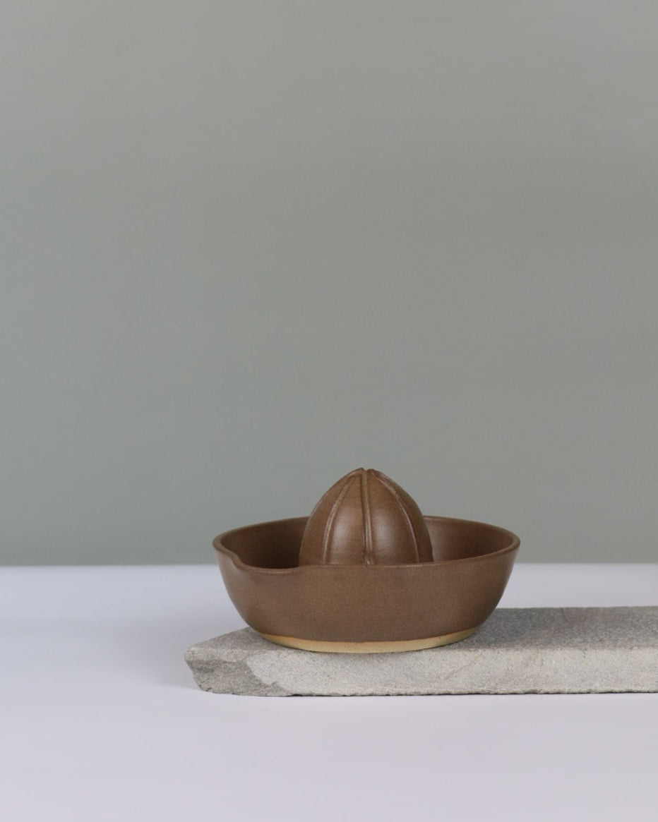 brown ceramic lemon juicer on a grey background