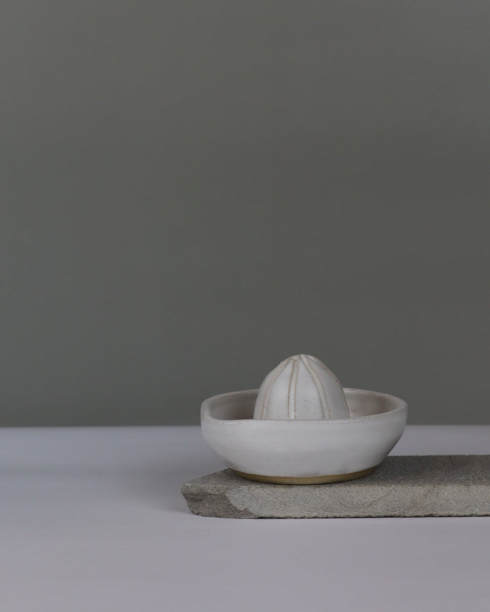 white ceramic citrus juicer on a grey background