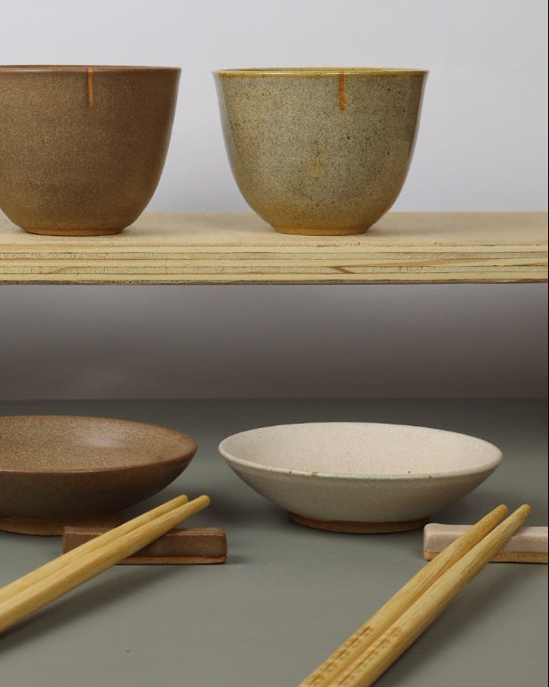 Set of ceramic bowls in various shapes and colors on a gray wall.