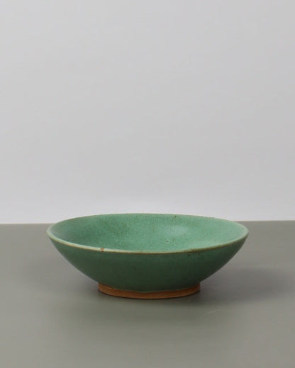 Green ceramic cup leaning against a white wall