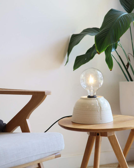 ceramic dome shaped lamp on a table with a plant in the background
