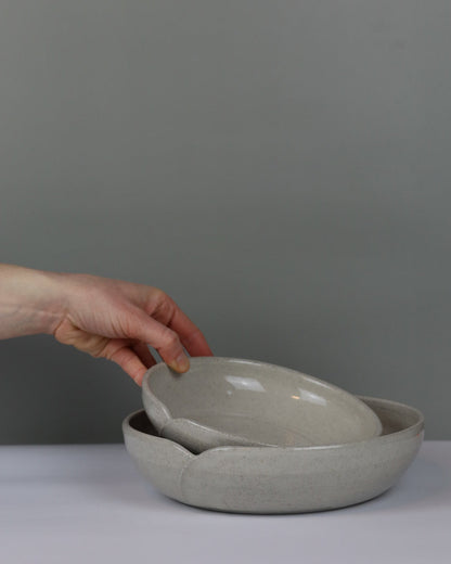Hand holding a cracked ceramic bowl against a plain background