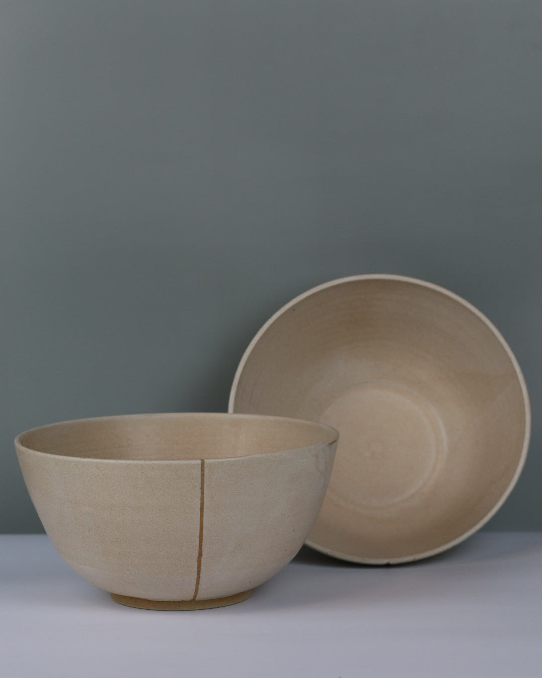 Two oatmeal ceramic ramen bowls on a grey background