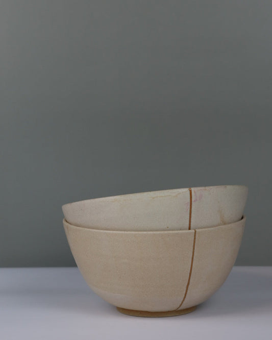 Stack of two beige ceramic bowls on a grey background