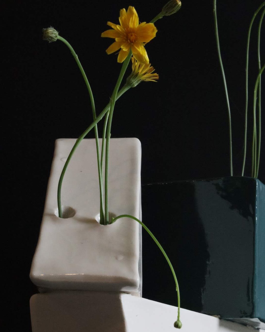 Abstract ceramic art piece with geometric shapes and flowers on a black background