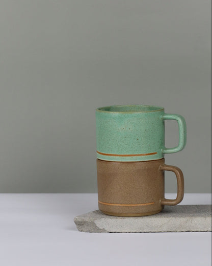 Two ceramic mugs, one brown and one green, stacked on top of each other.