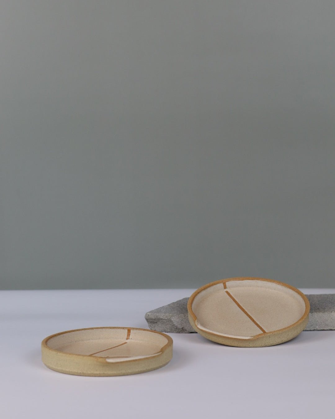 two ceramic spoon rests on a bench