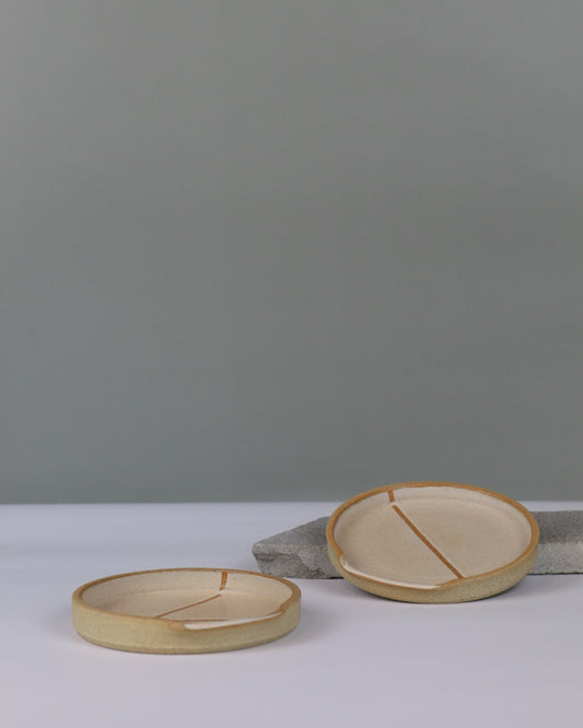 two ceramic spoon rests on a bench