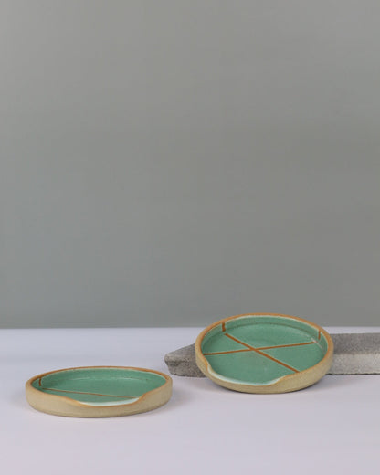 two ceramic spoon rests on a benchtop