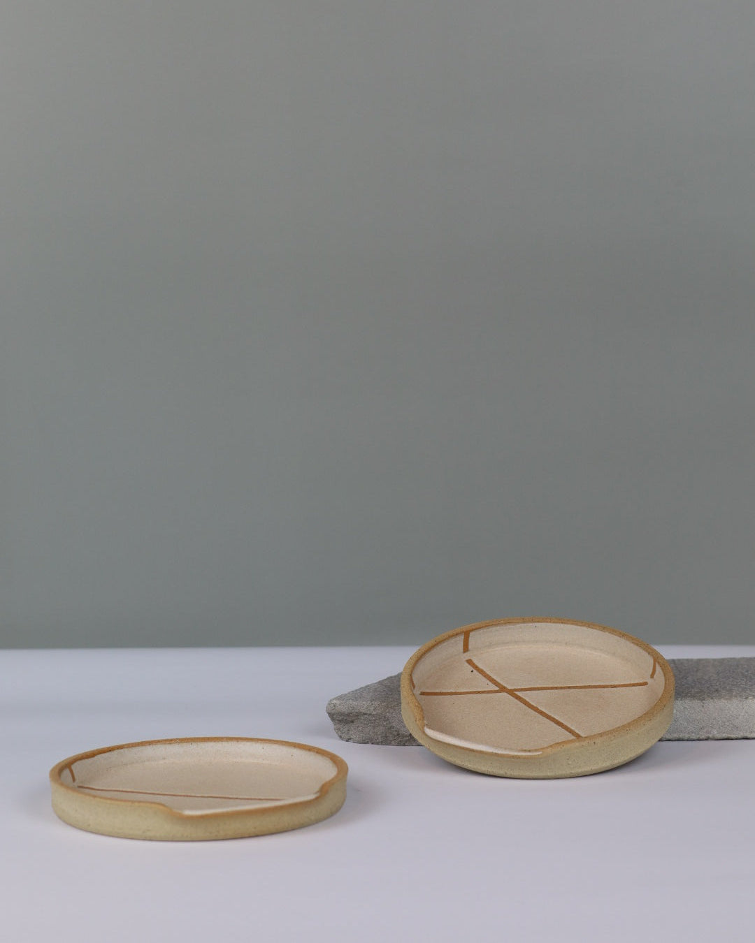 two ceramic spoon rests on a bench