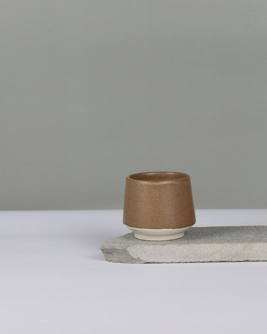 small brown ceramic tumbler against a grey background